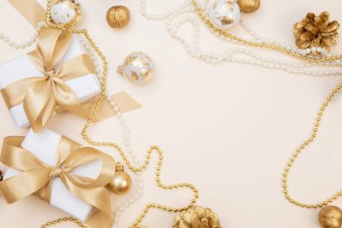 Beyaz hediyeler, altın fiyonklar ve bej arka planda ışıldayan süslemelerle süslü bir kış düzeni. Tebrik kartları, web pankartları ya da markalar için mükemmel.