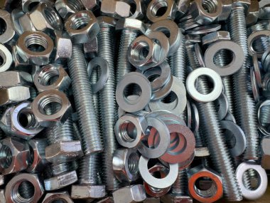 Metal cıvataları, fındıkları ve çamaşır makinelerini kapatın. İnşaat ve imalatta kullanılan endüstriyel donanım dokusu. Metal civatalar, fındıklar ve contalar endüstriyel doku arka planı olarak kapatılıyor.