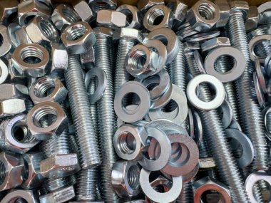 Metal cıvataları, fındıkları ve çamaşır makinelerini kapatın. İnşaat ve imalatta kullanılan endüstriyel donanım dokusu. Metal civatalar, fındıklar ve contalar endüstriyel doku arka planı olarak kapatılıyor.