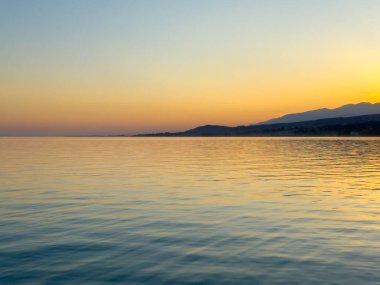 Kırgızistan 'daki Issyk Kul Gölü üzerinde gün batımı. Güneş dağların arkasında batar, suyun üzerinde altın bir yansıma bırakır. Kırgızistan 'daki Issyk Kul Gölü üzerinde gün batımında suyun üzerinde altın yansımasıyla.