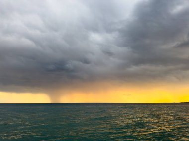 Kırgızistan 'daki Issyk Kul Gölü' nde gün batımı. Parlak güneş bulutları delip geçiyor ve turkuaz suyu yansıtıyor. Gün batımında Issyk Kul 'un turkuaz suyu altın yansıma ve dramatik bulutlarla.