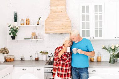 Yaşlı çift mutfakta çay içer.