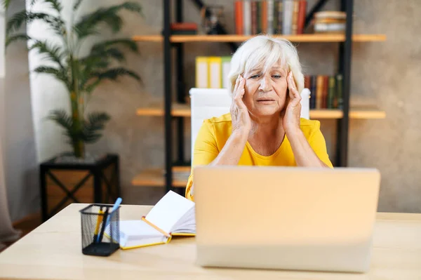 Cansada mulher de negócios sênior está usando laptop — Fotografia de Stock