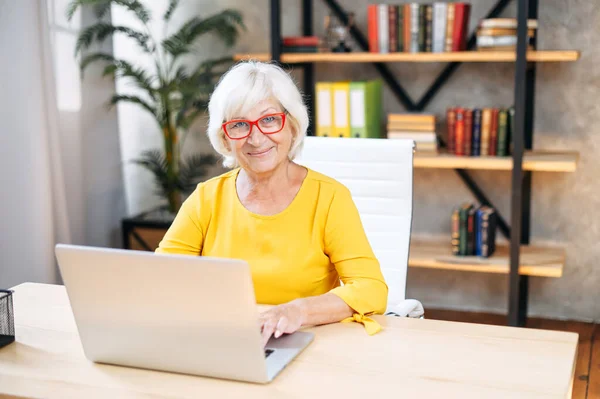 Старша жінка використовує ноутбук для роботи в приміщенні — стокове фото