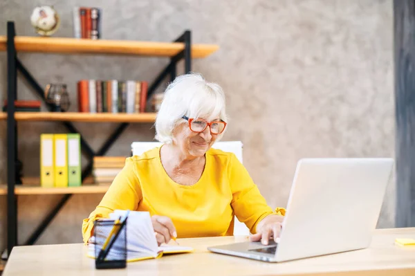 Femme âgée utilise un ordinateur portable pour travailler à l'intérieur — Photo