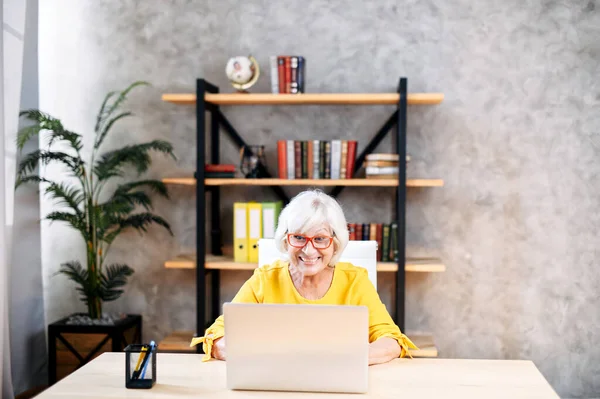 Senior woman is using laptop for work indoor — Stock Photo, Image