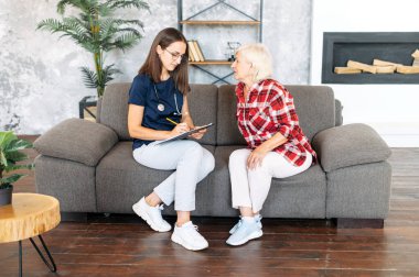 Evde yaşlı bir kadın hastaya danışmanlık yapan bir doktor.