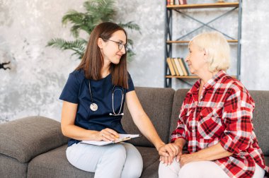 Evde yaşlı bir kadın hastaya danışmanlık yapan bir doktor.