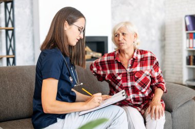 Evde yaşlı bir kadın hastaya danışmanlık yapan bir doktor.