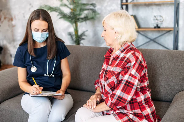 Doctor in medical mask and patient at home.