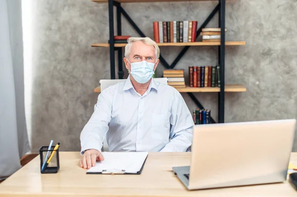 사무실에서 의료용 마스크를 쓰고 있는 노인 — 스톡 사진