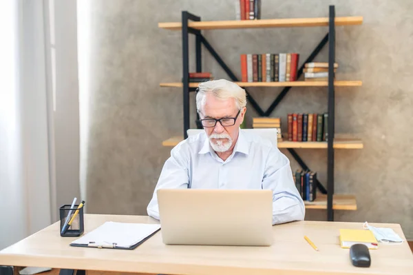 Senior grauhaarige Mann mit Laptop zu Hause — Stockfoto