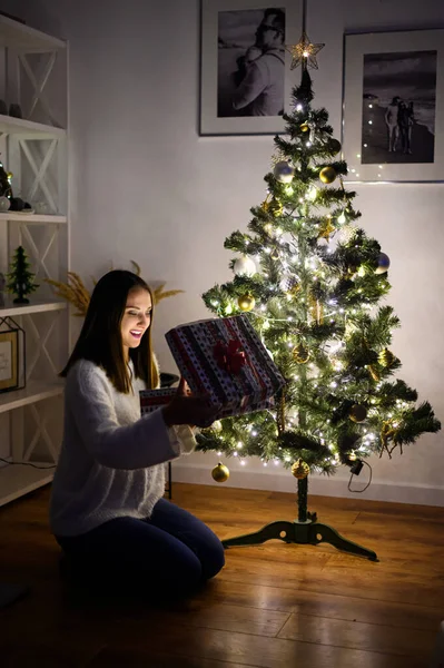 Mladá žena s dárkovou krabicí u vánočního stromku — Stock fotografie