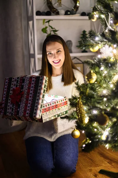 Una giovane donna con una scatola regalo vicino all'albero di Natale — Foto Stock