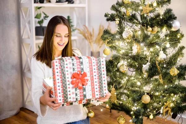 크리스마스 트리 근처에 선물 상자를 가지고 있는 젊은 여자 — 스톡 사진