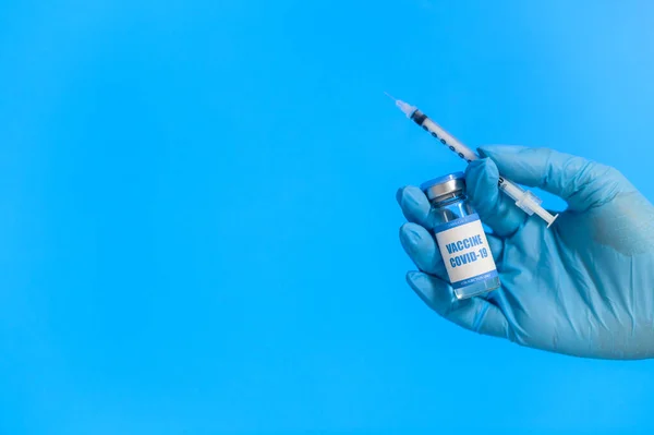 Mão na luva segura uma vacina e uma seringa — Fotografia de Stock