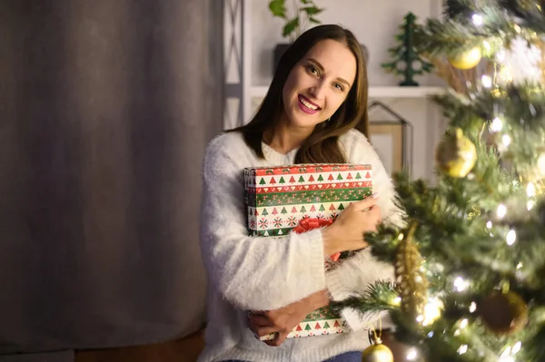Una donna con una scatola regalo vicino all'albero di Natale — Foto Stock