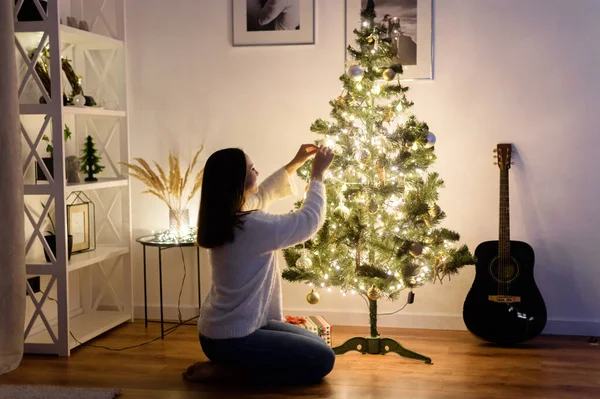 Een vrouw hangt kerstballen aan de boom — Stockfoto