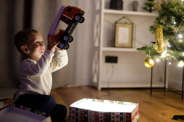 Un ragazzo carino con una scatola regalo vicino all'albero di Natale — Foto Stock