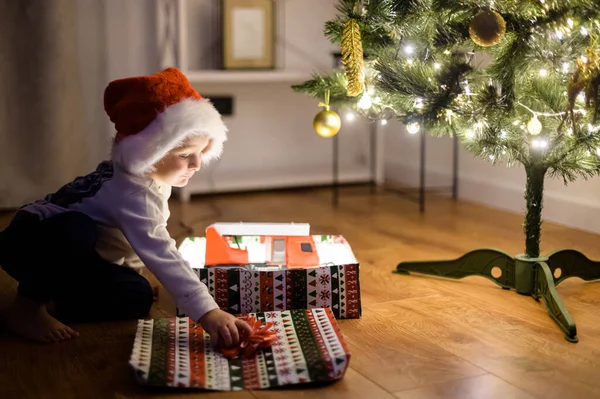 Um menino bonito com uma caixa de presente perto da árvore de Natal — Fotografia de Stock