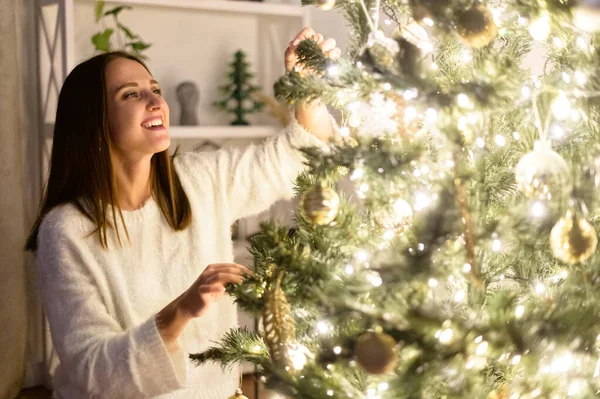 Μια γυναίκα κρεμάει Χριστουγεννιάτικα μπαλάκια στο δέντρο. — Φωτογραφία Αρχείου