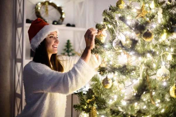 Uma mulher pendura bolas de Natal na árvore — Fotografia de Stock