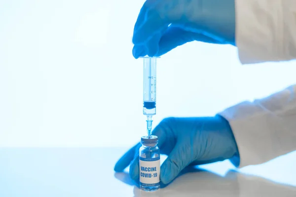 Handen in handschoenen houden een vaccin en spuit vast — Stockfoto