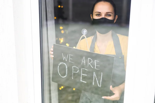 Mujer joven sosteniendo cartel abierto en la cafetería —  Fotos de Stock