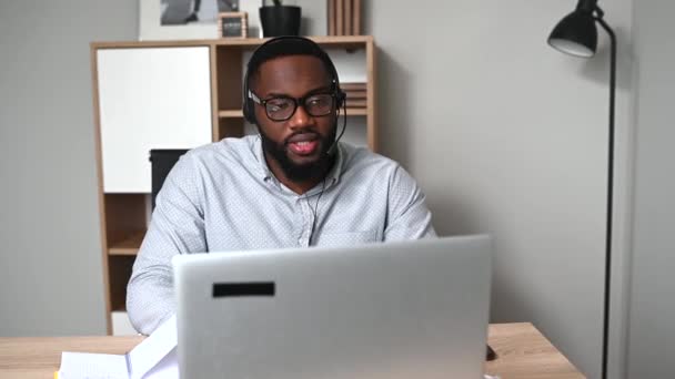 Een Afrikaan gebruikt een headset voor zijn werk. — Stockvideo