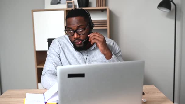 Un africano usa auriculares para trabajar. — Vídeos de Stock