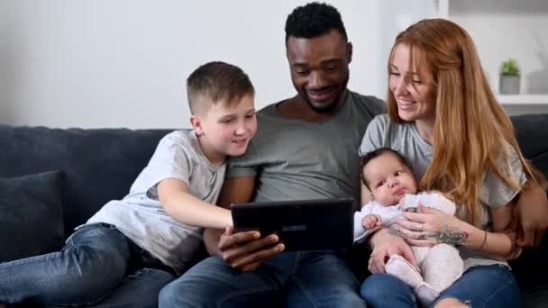 En lycklig multiracial familj på fyra med en tablett — Stockvideo