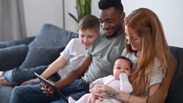 Una familia multirracial feliz de cuatro con una tableta — Vídeos de Stock