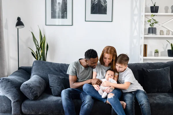 一个多种族的家庭坐在家里的沙发上 — 图库照片