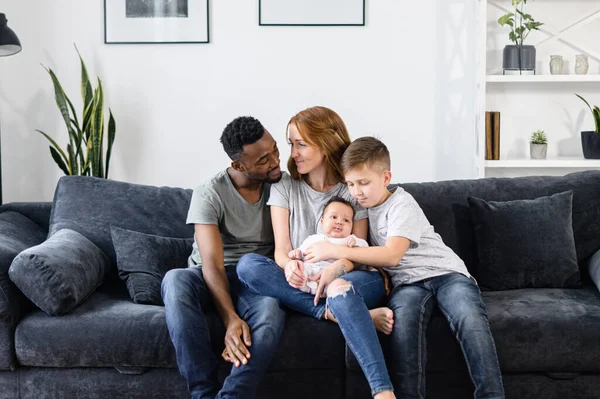 A multiracial family sits on the couch at home — Stock Photo, Image