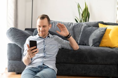 Serbest çalışan bir adam evde akıllı telefon kullanıyor.