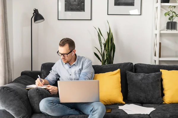 Een man met een laptop maakt aantekeningen. — Stockfoto