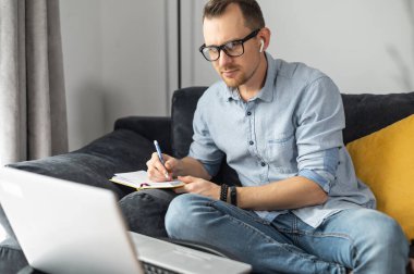 Not defterine dizüstü bilgisayarı olan genç bir adam.