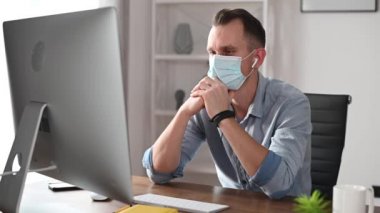 Ofiste bilgisayarını kullanan maskeli bir adam.