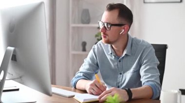 Genç bir adam ofiste bir bilgisayarla çalışıyor.