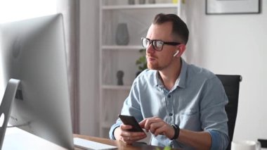 Genç bir adam ofiste bir bilgisayarla çalışıyor.