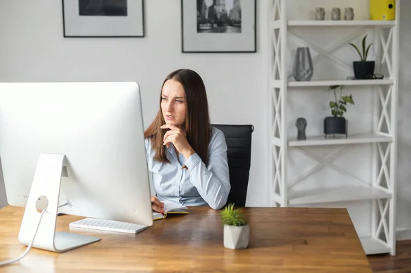 Молодая женщина пользуется компьютером в офисе — стоковое фото