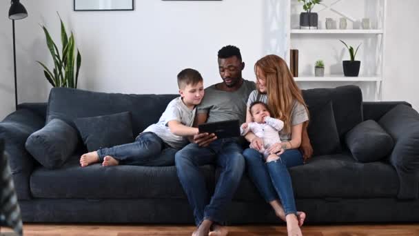 En lycklig multiracial familj på fyra med en tablett — Stockvideo