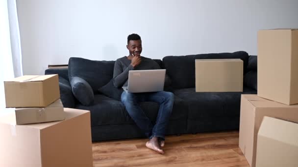 En afroamerikansk man med en laptop i soffan. — Stockvideo