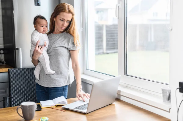 Eine junge Mutter nutzt Laptop für Fernarbeit — Stockfoto
