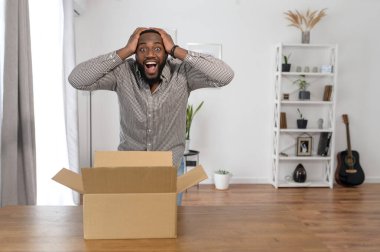 Adamın biri evde bir paket kutusu açıyor.