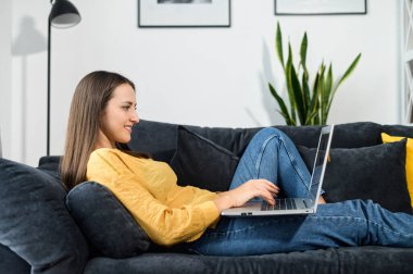 Evde dizüstü bilgisayarı olan genç bir kadın.