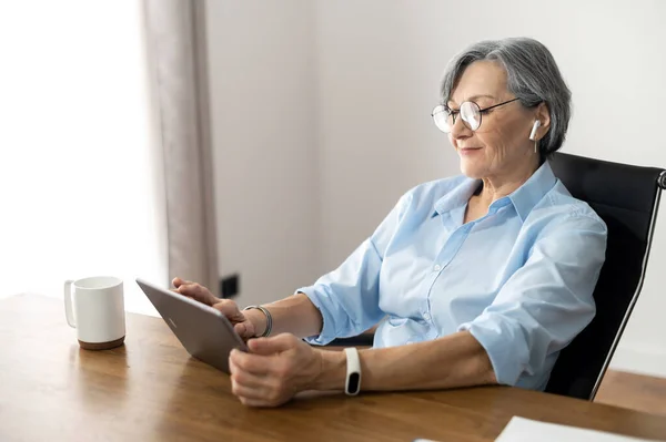 Старшая женщина офисный работник просматривает Интернет — стоковое фото