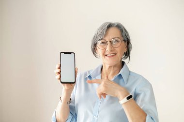 Kıdemli kadın akıllı telefon ekranını işaret ediyor.