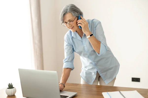 Multitasking senior businesswoman on a phone call — Stock fotografie