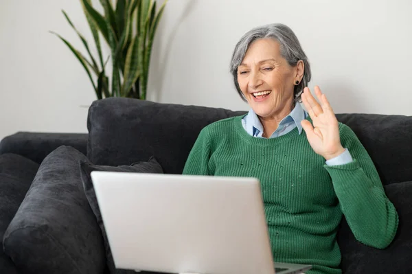 Glückliche Seniorin winkt am Laptop-Bildschirm — Stockfoto